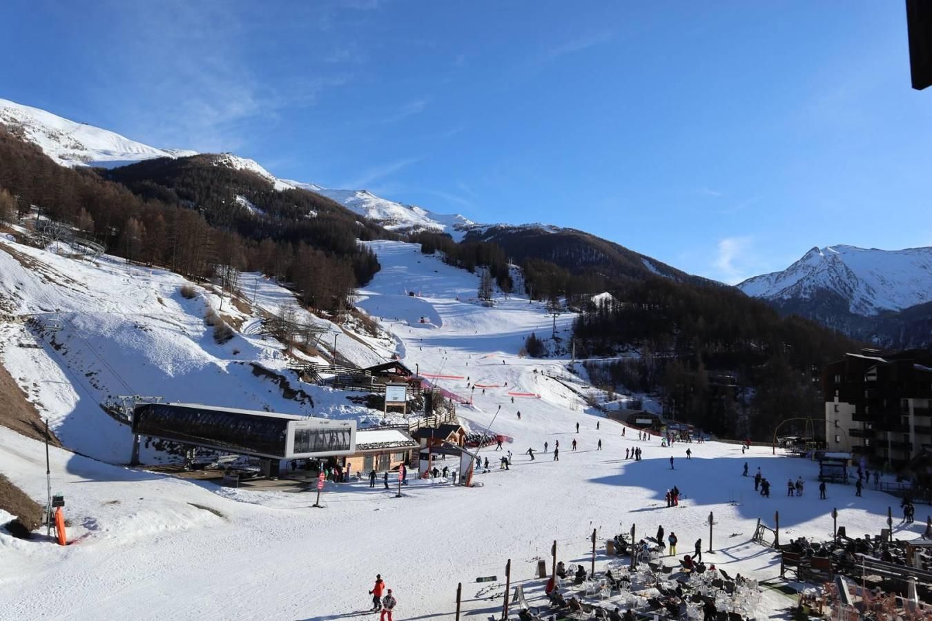 A ski resort with a chairlift, ski slopes, and buildings in the background.