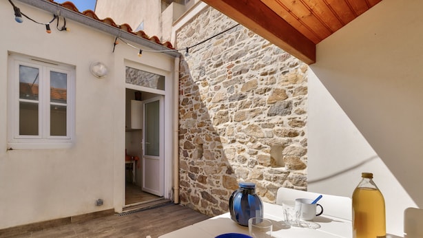 A small, cozy room with a stone wall, a wooden ceiling, and a table set with a bowl, glasses, a bottle, and croissants. - Getaway 150m from the beach in Les Sables d'Olonne (Les Sables-d´Olonne)