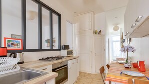 A modern kitchen with a sink, stove, oven, and microwave. There is a dining table with chairs and a vase of flowers. - Getaway 150m from the beach in Les Sables d'Olonne (Les Sables-d´Olonne)