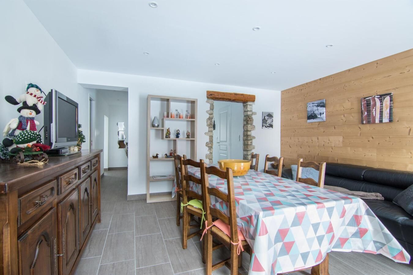 Een eetgedeelte met een tafel voor vier personen, houten stoelen, een buffetkast en een televisie op een kast.