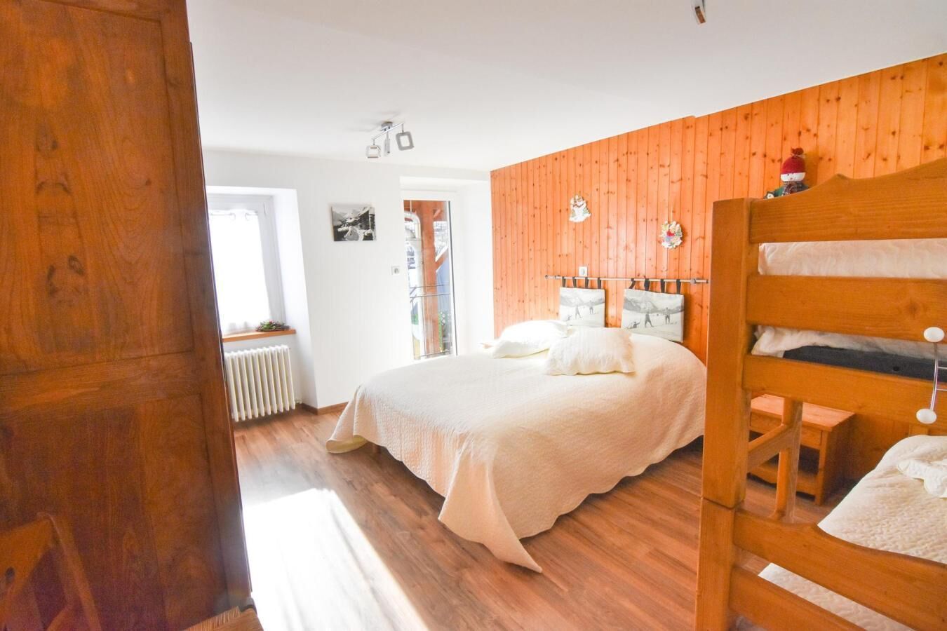 A bedroom with a wooden bed, a wooden headboard, a radiator, and a window.