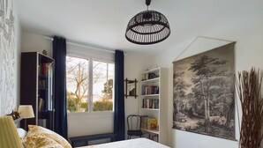Une chambre à coucher avec un lit, une bibliothèque, une fenêtre et un tableau.