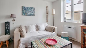 Un salon moderne avec un canapé blanc, une table à rayures colorées et une grande fenêtre.