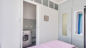 A bedroom with a pink bedspread, a washing machine, and a grey wardrobe. - Escape 400m from Sableaux beach (Noirmoutier-en-l´Ile)