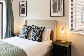 A neatly made bed with patterned pillows, a bedside lamp, and framed artwork on the wall. - Host & Stay | The Pilgrim House (Liverpool)