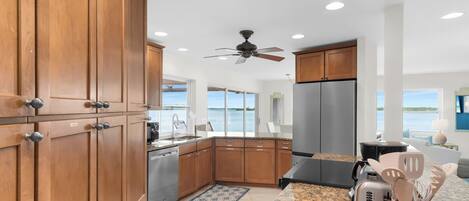 A modern kitchen with wooden cabinets, stainless steel appliances, and a view of the sea.