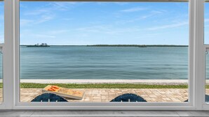A view from a window overlooking a calm body of water with a distant shoreline and buildings. - Waterfront 3/3 Home with Panoramic Bay Views! (Marco Island)