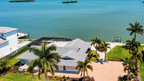 A coastal property with a large house, a swimming pool, and a view of the ocean. - Waterfront 3/3 Home with Panoramic Bay Views! (Marco Island)