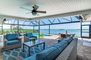 A covered outdoor area with wicker furniture, a pool, and a view of the ocean. - Waterfront 3/3 Home with Panoramic Bay Views! (Marco Island)