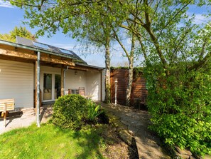 A house with a covered porch, a bench, and a small garden area with a pathway.