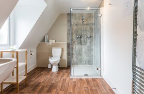 Bathroom features a glass-enclosed shower, toilet, and wooden vanity with a sink.