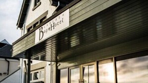 A hotel with a sign reading "Bay Hotel" and a balcony with potted flowers. - Lamlash Bay Hotel (Isle of Arran)