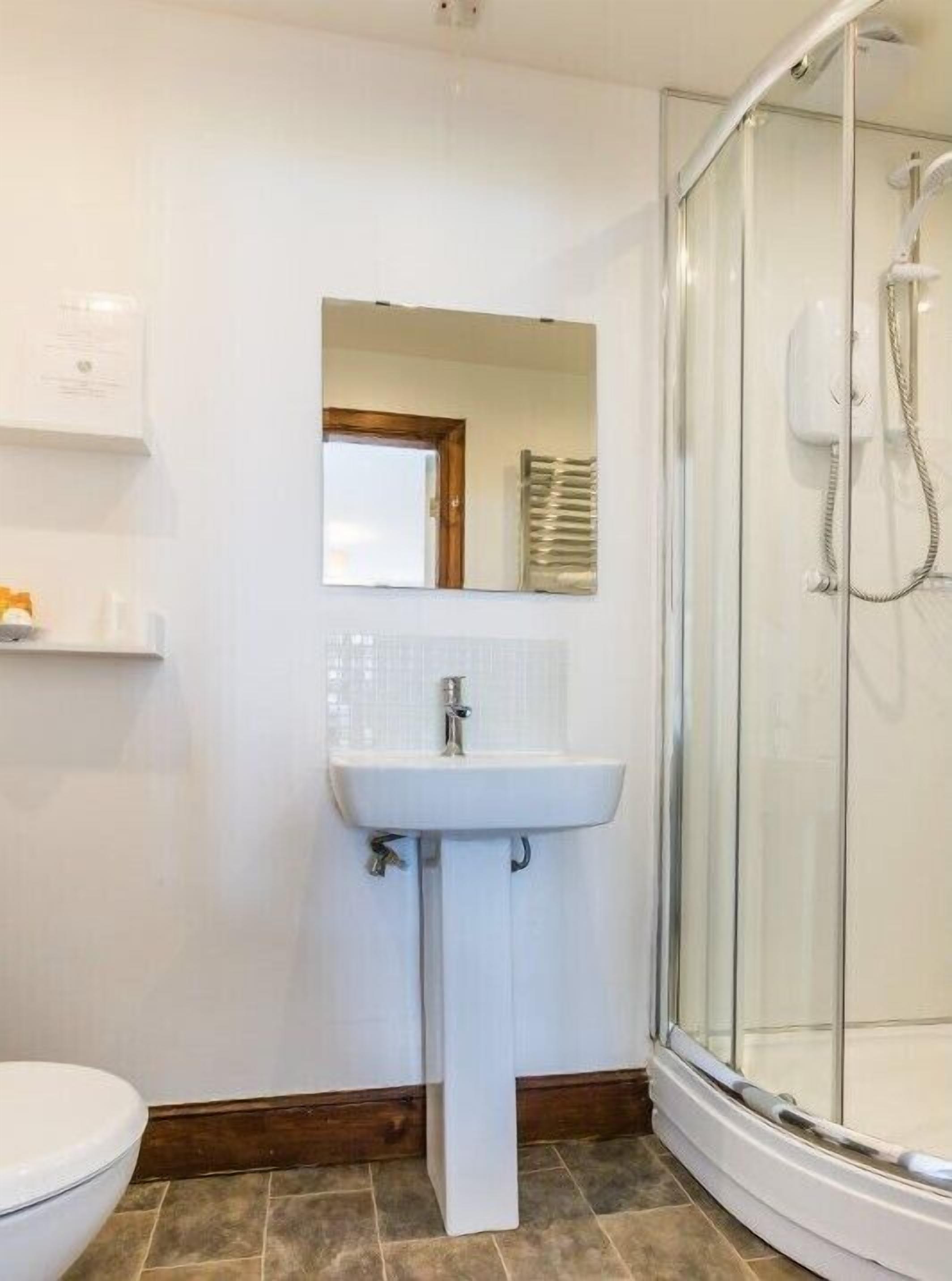 A bathroom with a white sink, a mirror, and a glass shower enclosure.