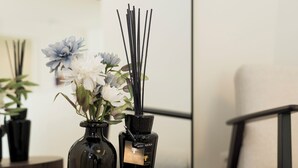 Una mesa redonda de madera con dos jarrones negros que contienen flores y difusores de aroma.