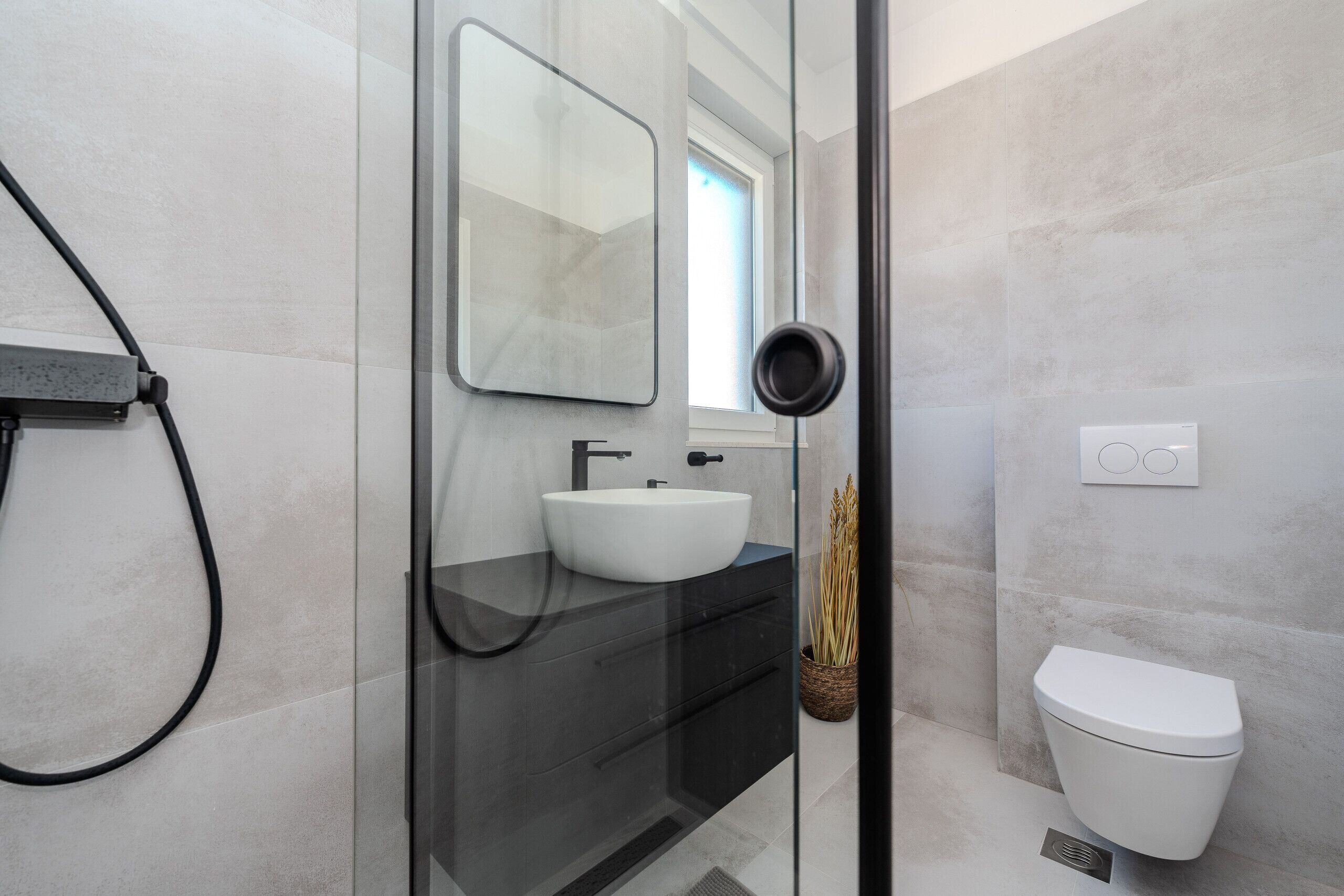 A modern bathroom with a glass shower enclosure, a white sink, and a toilet.