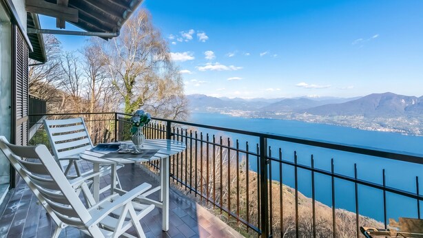 A balcony with a table and chairs, overlooking a lake and mountains. - Lago Azzurro Villa: Infinity Lake View (Premeno)