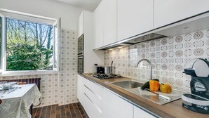 A modern kitchen with white cabinets, a wooden countertop, a gas stove, a sink, and a window with a view of trees. - Lago Azzurro Villa: Infinity Lake View (Premeno)