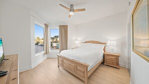 Quarto com cama, abajures, ventoinha no teto e janela com cortinas.