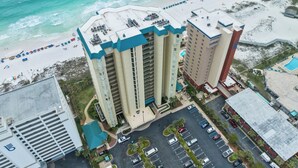 Un hotel moderno de gran altura con varios pisos, estacionamiento y vista al mar.