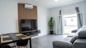 A modern living room with a flat-screen TV, a dining table with chairs, a grey sofa, and a potted plant. - Domus Gades        . (Chiclana)