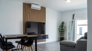 A modern living room with a dining area, featuring a large flat-screen TV, a potted plant, and a view of the outdoors. - Domus Gades        . (Chiclana)