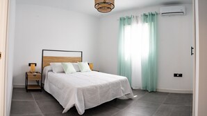A bedroom with a bed, bedside tables, a lamp, and a window with curtains. - Domus Gades        . (Chiclana)