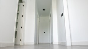 A hallway with white walls and a grey floor, leading to a door at the end. - Domus Gades        . (Chiclana)