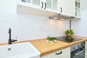 A modern kitchen with white cabinets, a wooden countertop, and stainless steel appliances. - Evergreen Escape (Dubrovnik)