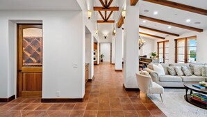 Un amplio salón con chimenea, un comedor y una cocina visibles a través de una puerta abierta.
