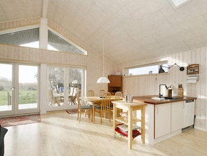 A spacious room with a wooden dining table, chairs, and a kitchen area with a sink and cabinets. - 4 Star Holiday Home in Gorlev (Gørlev)