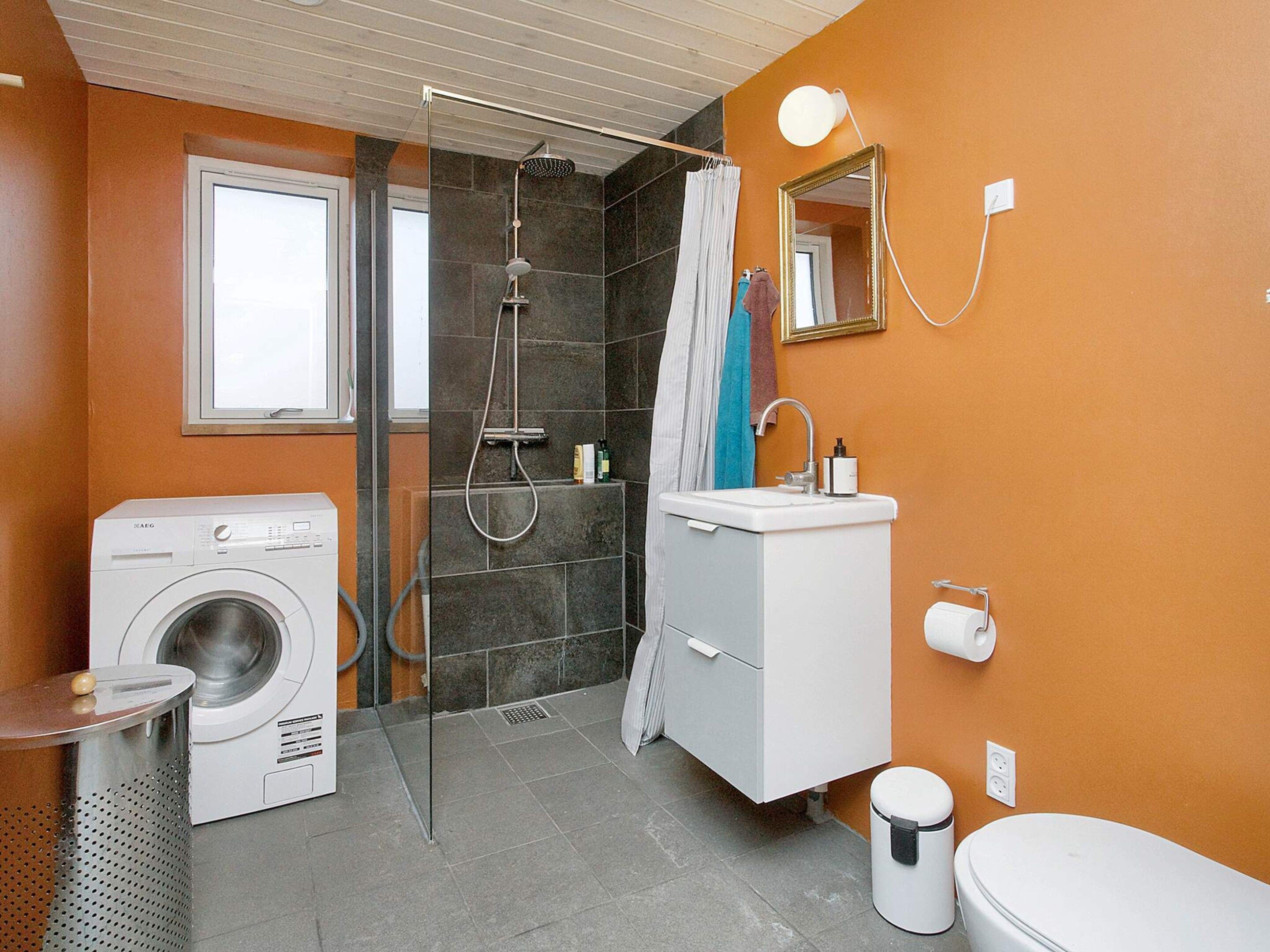 Et stilfuldt badeværelse med vaskemaskine, bruser, håndvask og toilet.