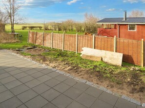 A paved walkway leading to a fenced area with a red building and a chimney. - 4 Star Holiday Home in Gorlev (Gørlev)