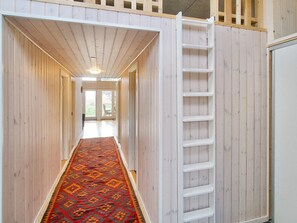 A narrow hallway with a wooden floor and a patterned rug, leading to a door with a view of the outdoors. - 4 Star Holiday Home in Gorlev (Gørlev)
