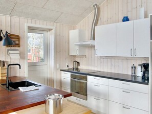 A modern kitchen with a wooden interior, stainless steel appliances, and a black countertop. - 4 Star Holiday Home in Gorlev (Gørlev)