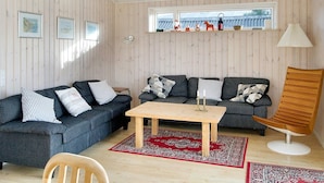 A cozy living room with a wooden ceiling, a sofa set, a coffee table, a wooden chair, and a window with decorative items. - 4 Star Holiday Home in Gorlev (Gørlev)