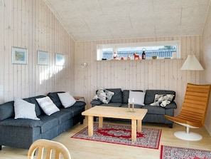 A cozy living room with a wooden ceiling, a sofa set, a coffee table, a wooden chair, and a window with decorative items. - 4 Star Holiday Home in Gorlev (Gørlev)