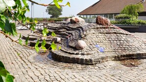 A historical stone structure with circular patterns and a modern building in the background. - 5 Person Holiday Home on a Holiday Park in Karrebaeksminde (Karrebæksminde)