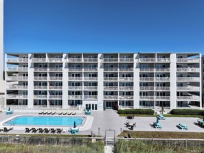 Ein mehrstöckiges Hotel mit Schwimmbad, Außenbereich und Balkonen.