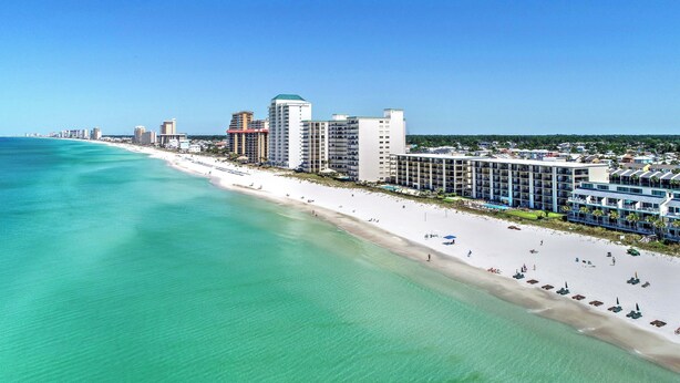 A coastal hotel with multiple floors, a beachside location, and a view of the ocean.