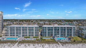 A modern hotel with multiple floors, a pool area, and a beach view.