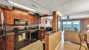 A kitchen with dark wood cabinets, a black microwave, and a tiled backsplash.
