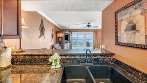 A kitchen with granite countertops, a black sink, and a ceiling fan.