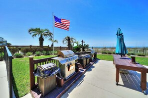 Ein Grillplatz mit Grill, Tisch und Sonnenschirm, einschließlich einer Flagge.