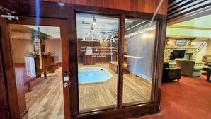 Una porta in legno che dà su una stanza con una vasca idromassaggio e un camino in pietra.