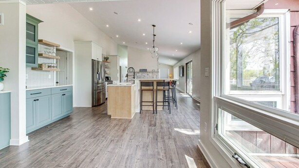 A spacious kitchen with a central island, light blue cabinets, and a large window.
