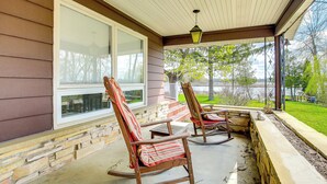 A porch with two rocking chairs, a stone wall, and a view of a lake.