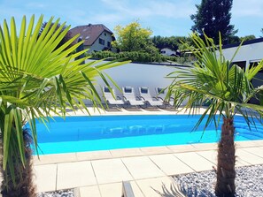 Una piscina con lettini e palme.
