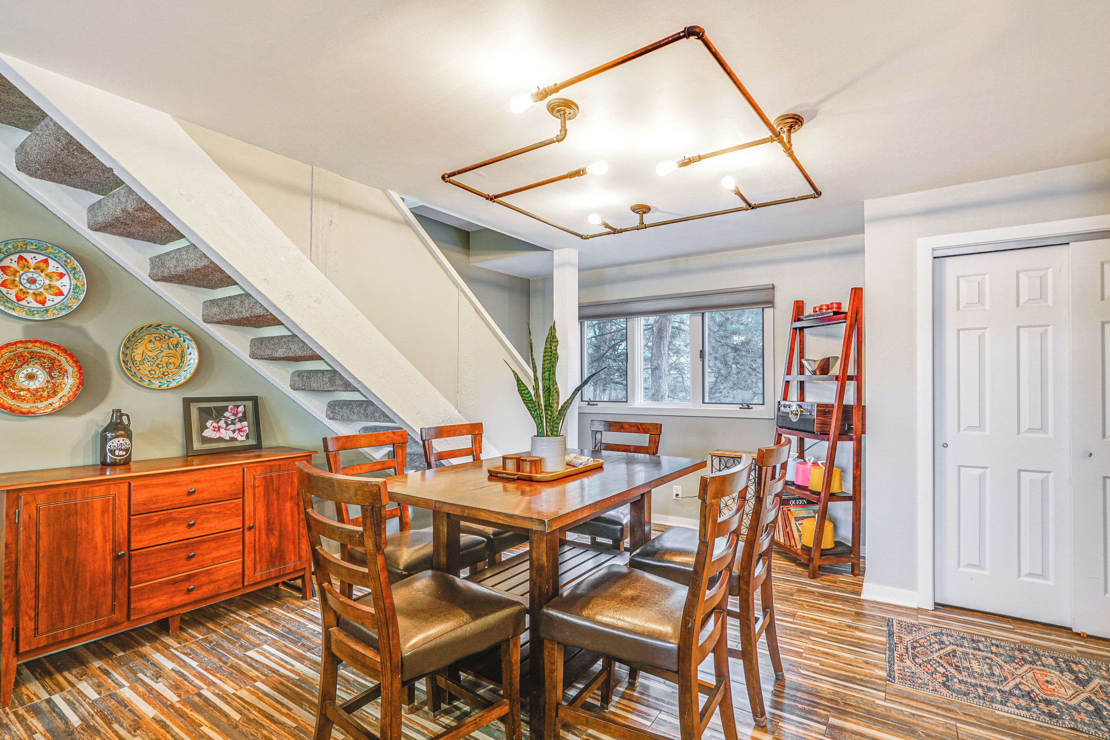 A dining area with a wooden table and chairs, a staircase, and a bookshelf.