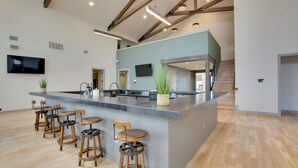 Une cuisine spacieuse dotée d’un grand îlot central, de tabourets de bar et d’un escalier menant à un niveau supérieur.