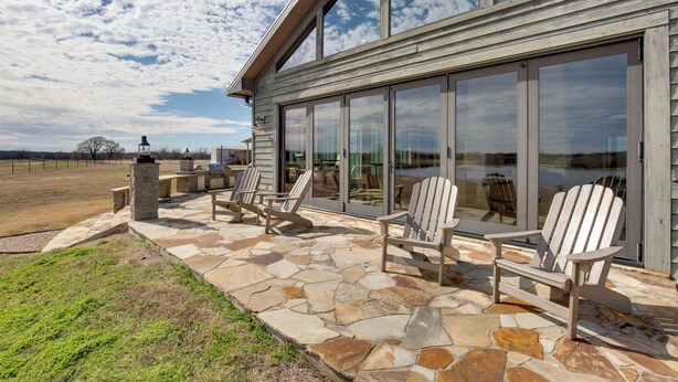 Une terrasse en pierre avec des fauteuils Adirondack et une lanterne en pierre.